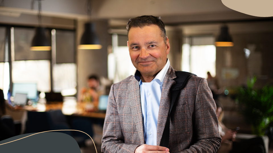 Markkinointikonsultti toimistoympäristössä hymyilee kameralle ja kantaa olkalaukkua; kuva edustaa pienyrityksen henkilökohtaista palvelua.